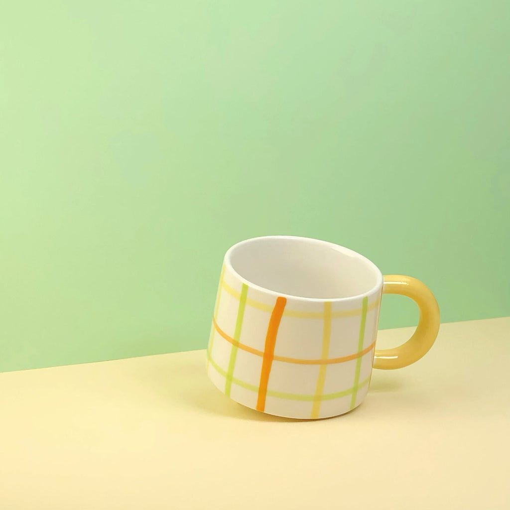 Mug with a yellow handle on a light green background